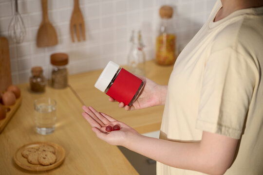 Woman holding a jar of supplements with two gummies in her hand
