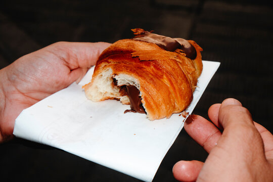 a man holds a chocolate-filled croissant