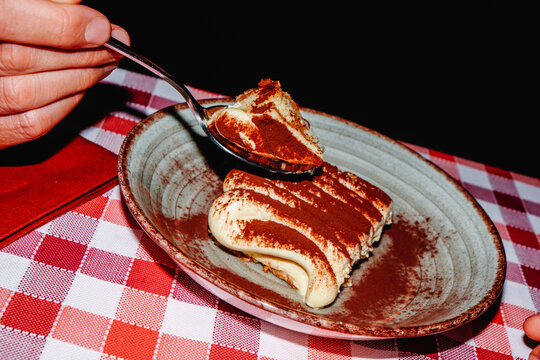 man lifting a spoonful of creamy tiramisu