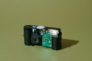 a disassembled disposable film camera on olive surface