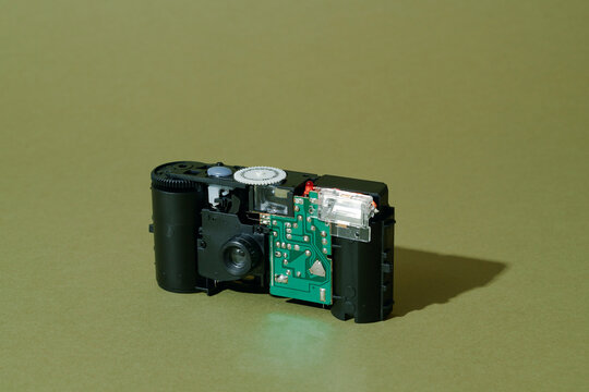 a disassembled disposable film camera on olive surface