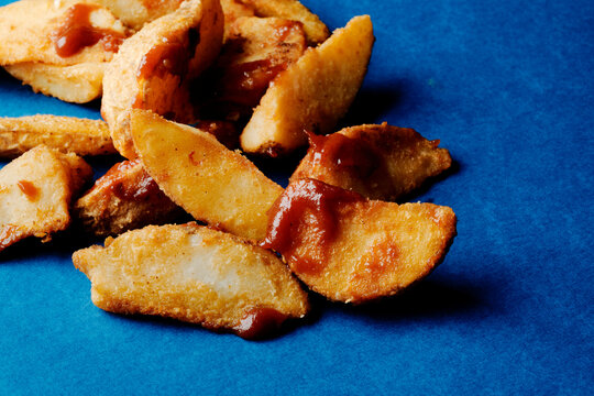 crispy potato wedges with ketchup on blue