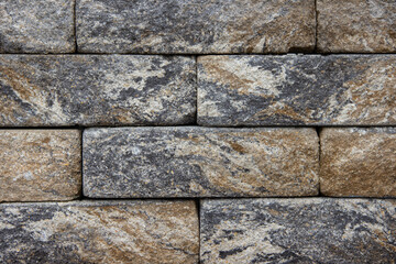 Textured stone wall featuring a variety of gray and brown hues, showcasing the natural beauty of the materials in a structured arrangement for architectural design inspiration