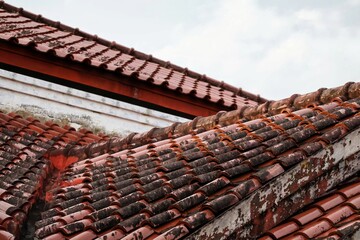 Red clay roof tiles on blue sky background. Traditional terracotta roof pattern on residential roof.