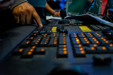 Lighting engineer hand operating control console at event