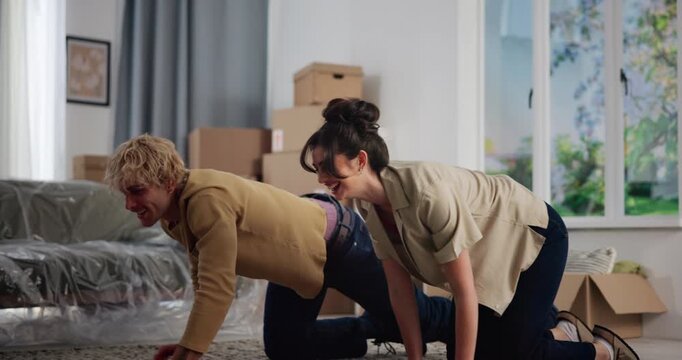 Couple, rolling carpet and happy in new home, moving and interior design for flooring with real estate. Man, woman and helping hand with partner, mat and boxes at apartment, relocation and property - Powered by Adobe