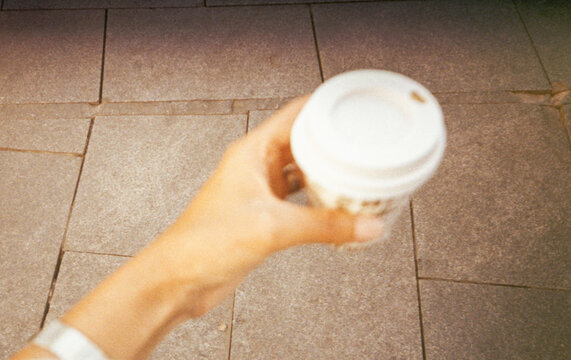 Film UGC image of hand holding takeaway coffee from above