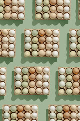 Natural colored eggs in packaging, green brown white colorful Chicken egg on green background, creative food pattern. Minimal Easter holiday, top view still life photo, festive eco friendly food.