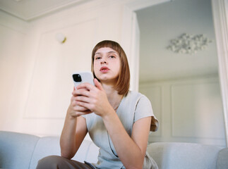 Woman sitting on sofa checking phone
