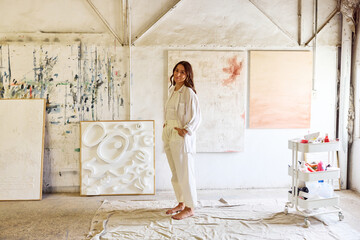 Artist in bright studio with abstract art and tools