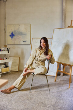 Artist poses thoughtfully in a creative studio setting