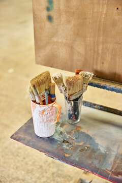 Brushes in a container on a workshop table ready for painting ta