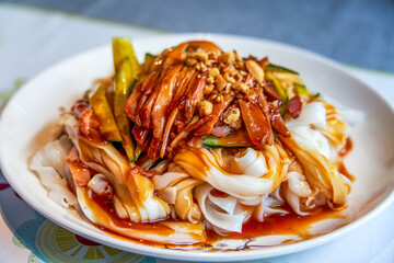 A plate of sweet and sour traditional Guangxi-style dry rice noodles with char siu