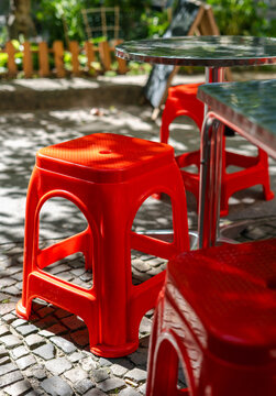 Red plastic stools and metal tables on a stone sidewalk