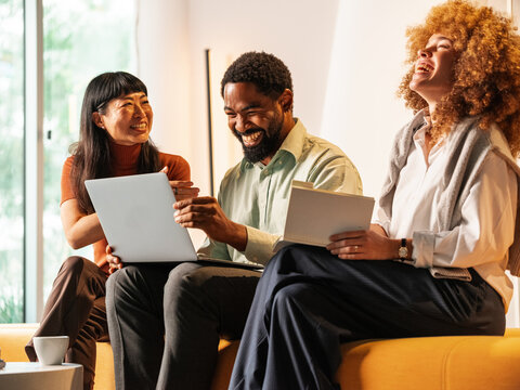 Three Friends Laughing Together During a Casual Business Meeting
