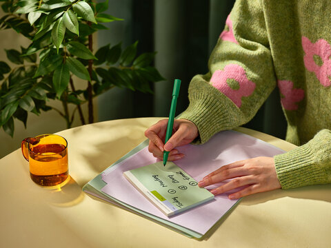 Someone writes down a meeting agenda on a notepad with a cup of tea