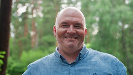 portrait of handsome dad standing outdoors in lush arboretum, smiling softly while enjoying tranquil summer atmosphere, showing warmth, happiness, and calm presence surrounded by sunlight