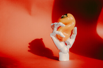 Robotic hand with orange pepper on red