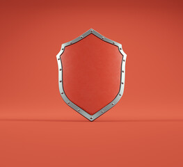 Metallic shield with studs displayed against a vibrant red background in a studio setting showcasing its design and texture