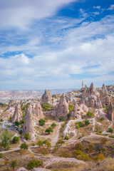 Naklejka premium A breathtaking view of Cappadocia’s iconic fairy chimneys rising from a rugged valley in Turkey. The landscape features cone-shaped rock formations, ancient cave dwellings carved