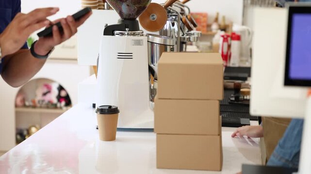 Courier and female small business entrepreneur verifying package via mobile device inside coffee shop, representing modern cashless payment, delivery service reliability, collaboration online orders - Powered by Adobe