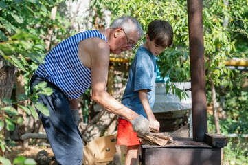 Grandfather teaching grandson to light outdoor stove, Grandfather and grandson preparing food on an outdoor stove in the backyard