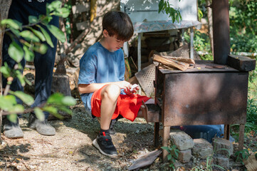 Grandfather teaching grandson to light outdoor stove, Grandfather and grandson preparing food on an outdoor stove in the backyard