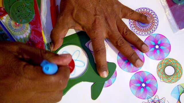 Mature hands drawing detailed colorful floral and geometric mandalas with circular symmetrical design patterns using round stencil