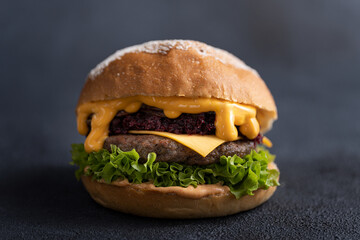 Burger with Beef Patty, Melting Cheese Drip, Beetroot Relish and Fresh Lettuce on Dark Background — Gourmet Food Presentation