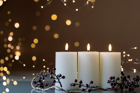 Advent white candles with decor in shiny lights closeup