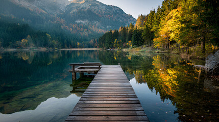 Wooden pier on a serene alpine lake with mountain and forest reflection
