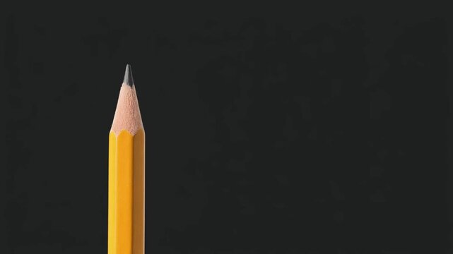 Close-up of yellow pencil with graphite tip against dark background ready for writing or drawing related creative work