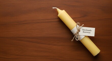 Handmade beeswax candle with label on a dark wood background top view