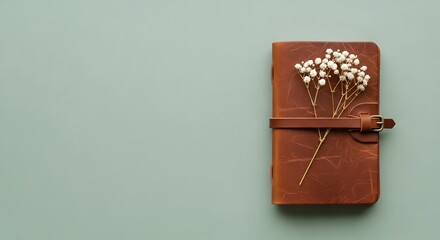 Rustic leather journal with dried flowers on a soft blue background