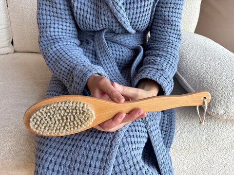 Woman using dry body brush at home during self-care routine