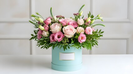 Elegant pink and white roses in a turquoise gift box on white table