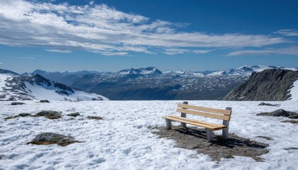 Wooden park bench situated on a snowy mountain plateau overlooking distant peaks under a bright sky