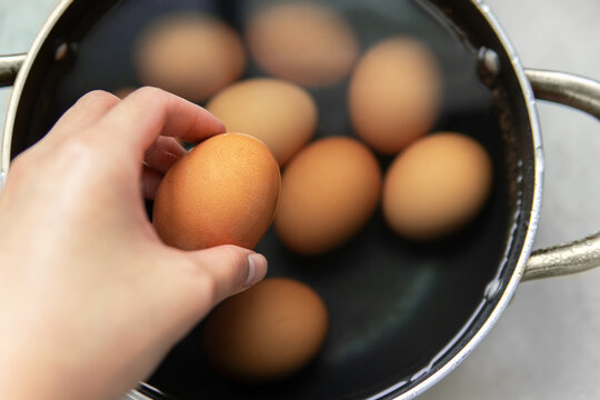 Hand Taking Cooked hard boiled egg out from a pot 