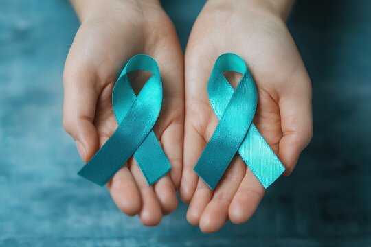 Hands holding teal ribbons symbolizing awareness on a blue textured background showcasing commitment to important causes - Powered by Adobe