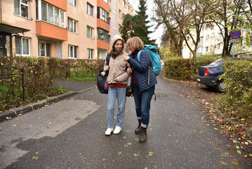 Obraz premium Mother and young adult daughter walking arm in arm on an urban street