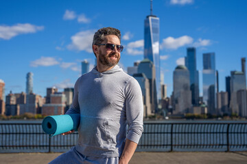 Sportsman in New York. Man in sportswear with fitness mat in Manhattan. Fit your body. Yoga coach. Sport man ready for workout. Healthy lifestyle. Fitness and sport. Yoga mat for training, copy space