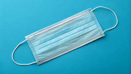 Protective face mask on a blue background, symbolizing health and safety during the pandemic and everyday life in modern times