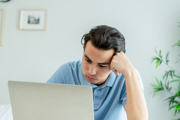 Depressed Asian man freelancer using laptop device working in house. 