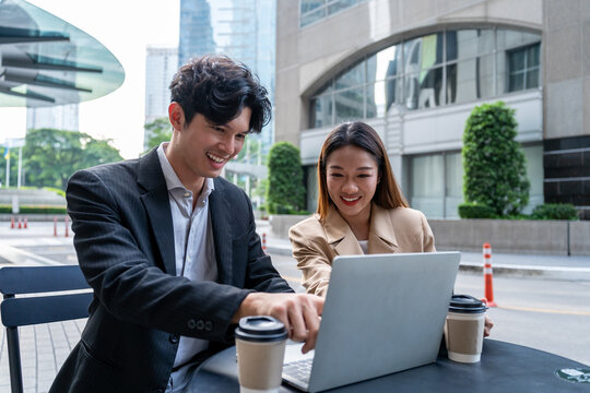 Asian young businessman and woman partner working outdoors in city. 