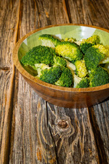 Large round dish with broccoli on a wooden table. 