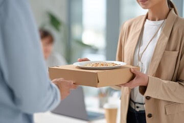 Businesswoman receives food delivery at modern office during lunchtime with colleagues nearby engaged in work activities