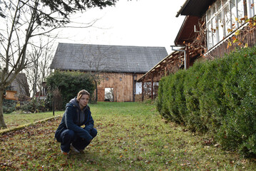 Young woman crouching in a rustic farmyard