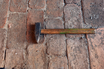 Vintage masonry hammer on a brick floor