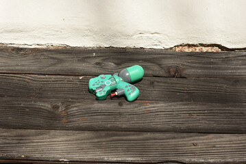 Green plastic dinosaur shaped water gun on rustic wood