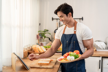Asian man cooking healthy foods in cozy kitchen in morning at home